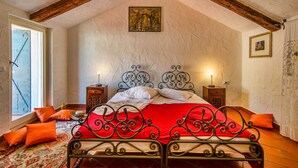 A bedroom with a sloped ceiling, a bed with ornate metal headboard, two bedside tables with lamps, and a patterned rug. - Villa Marko (Vrsar)