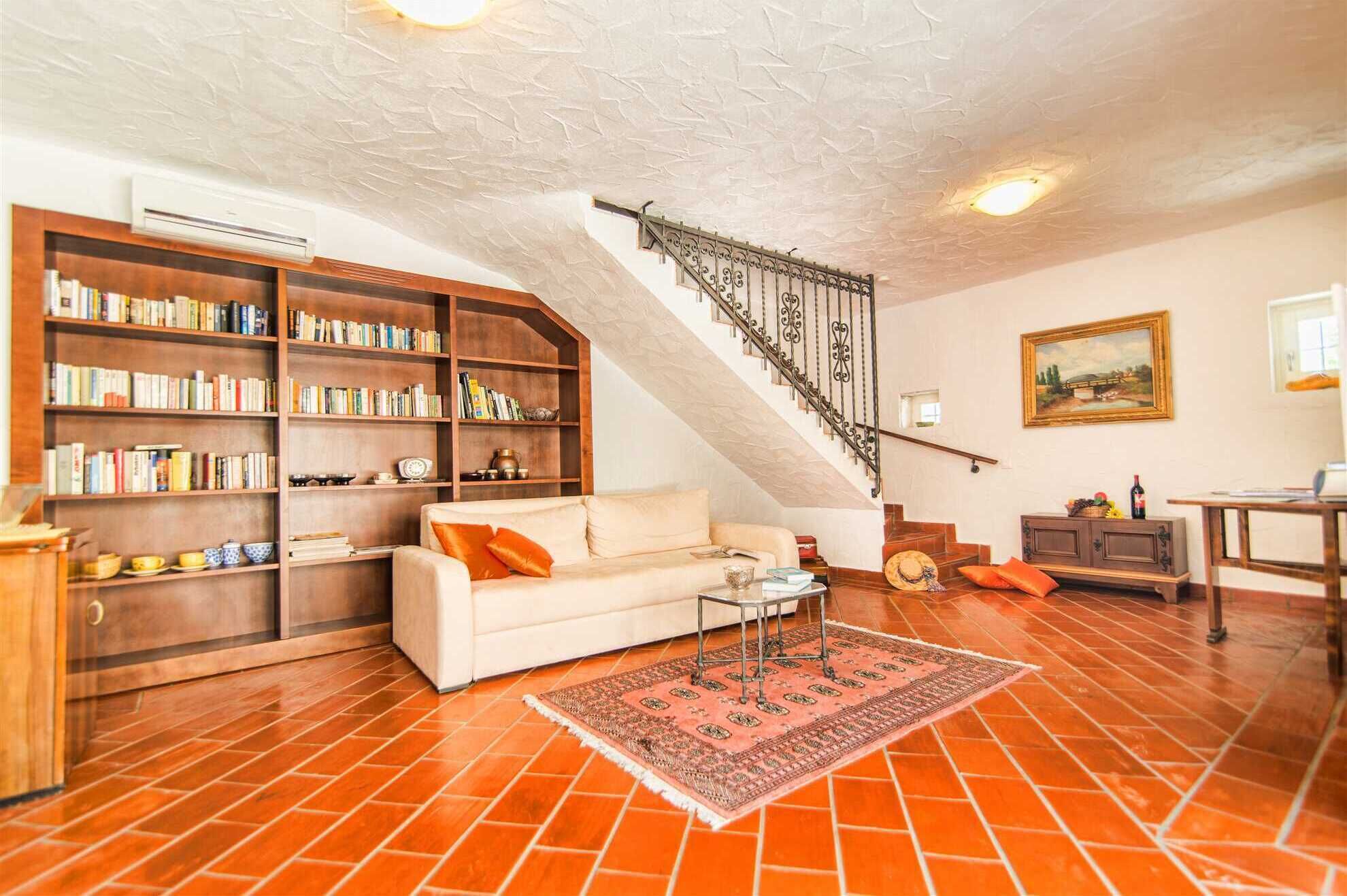 Un salon avec un canapé, des étagères, un escalier et un tableau au mur.