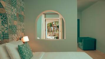 Un dormitorio con cama, una ventana en arco, una mesita de noche con lámpara y vistas a un espacio exterior con sillas y una mesa.