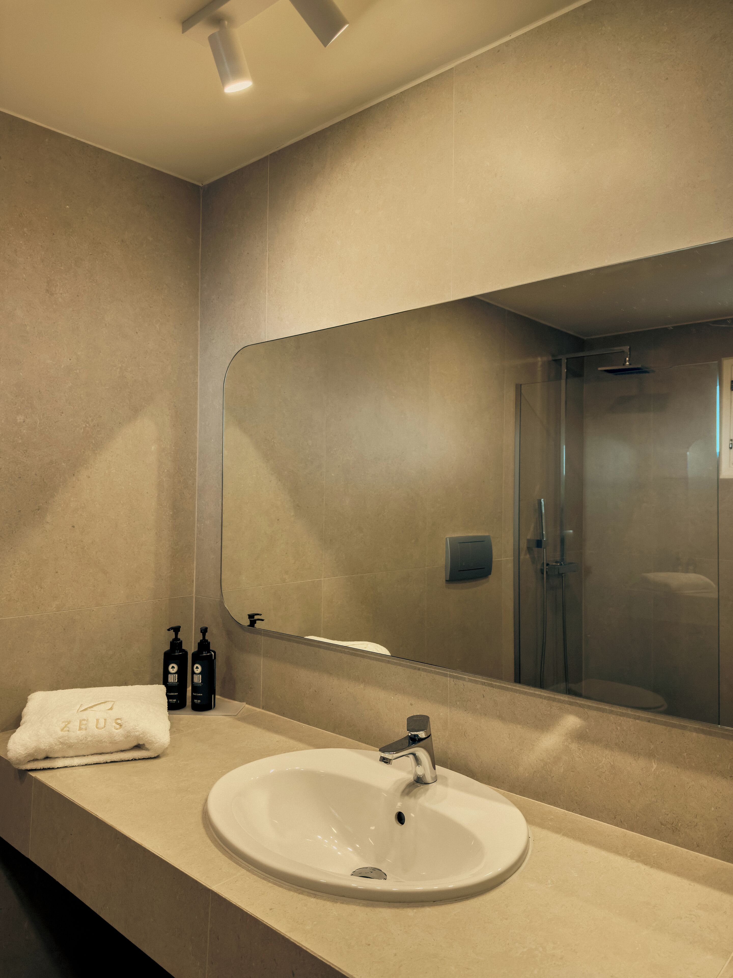 A bathroom with a sink, mirror, and shower.