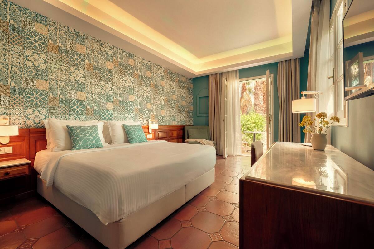 Een hotelkamer met een groot bed, een bureau en uitzicht op de omgeving.