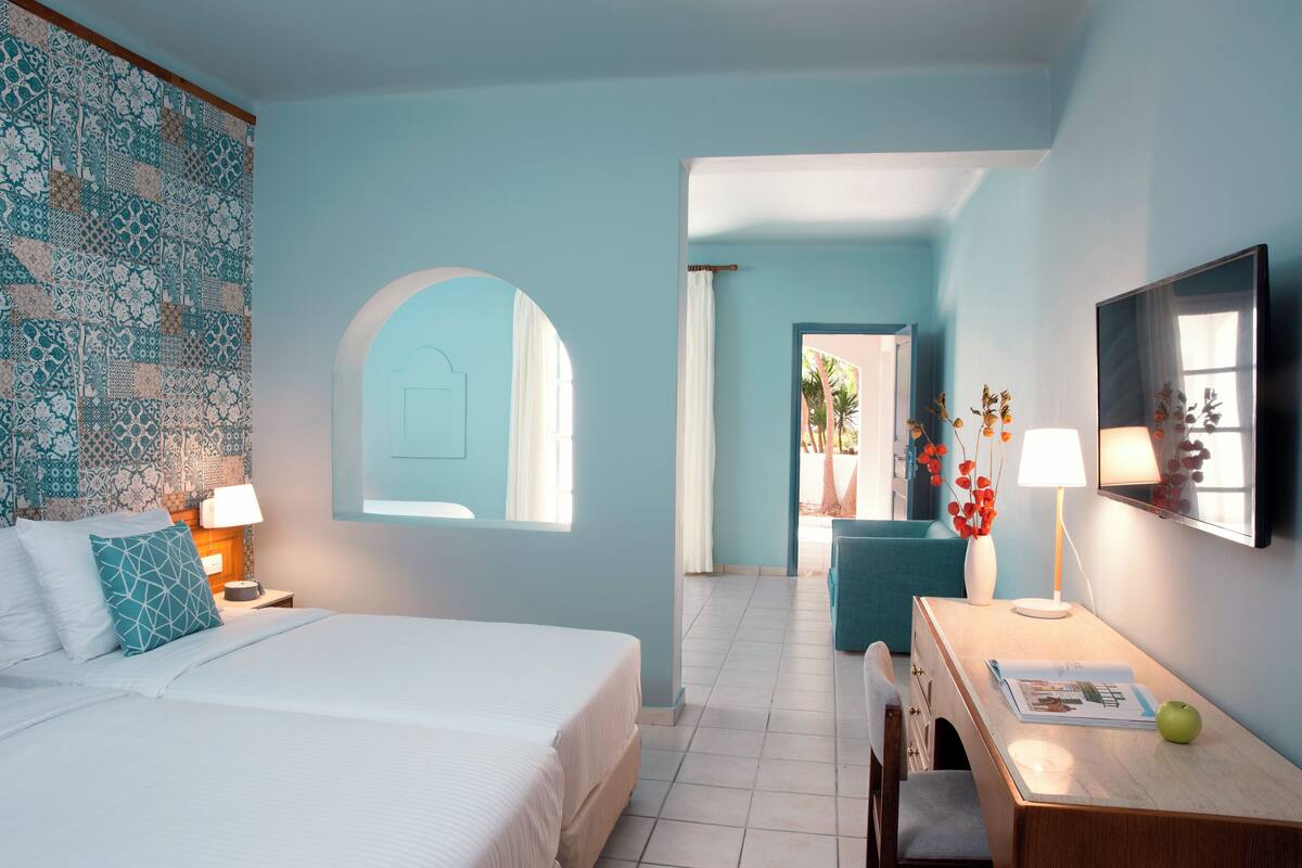 Een hotelkamer met een bed, een bureau, een stoel, een lamp en een raam.