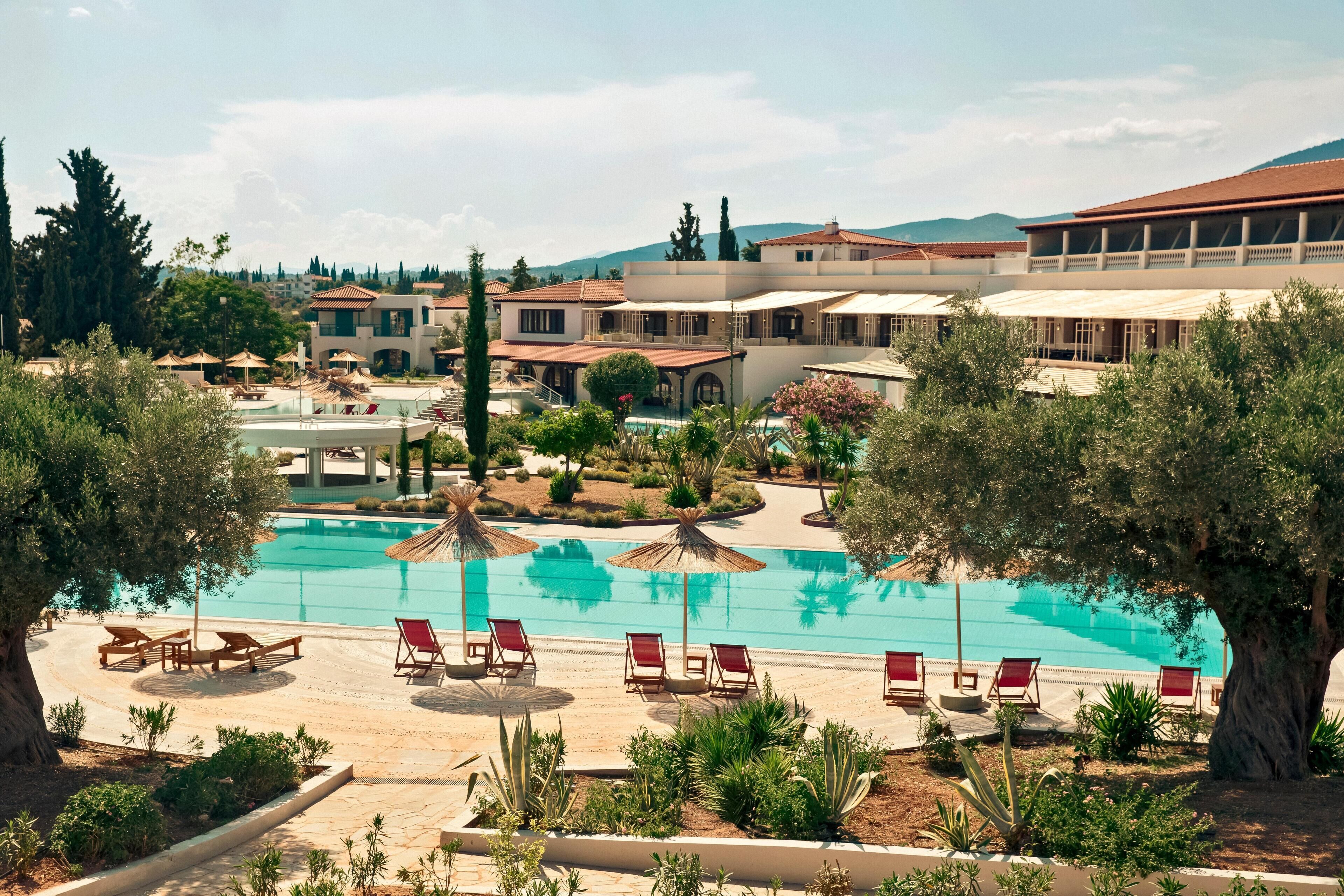 Ein Resort mit Schwimmbad, Liegestühlen und einem angelegten Garten.