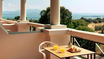 A balcony with a table set for two, two glasses of orange juice, a plate with croissants, and a vase with flowers.