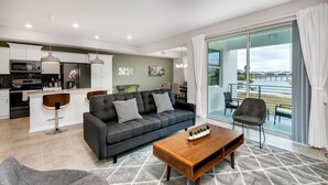 Ein modernes Wohnzimmer mit grauem Sofa, Holztisch und Blick auf den Balkon.