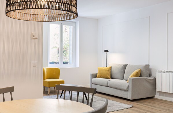 Un salon moderne avec un canapé, un fauteuil jaune et une table à manger.