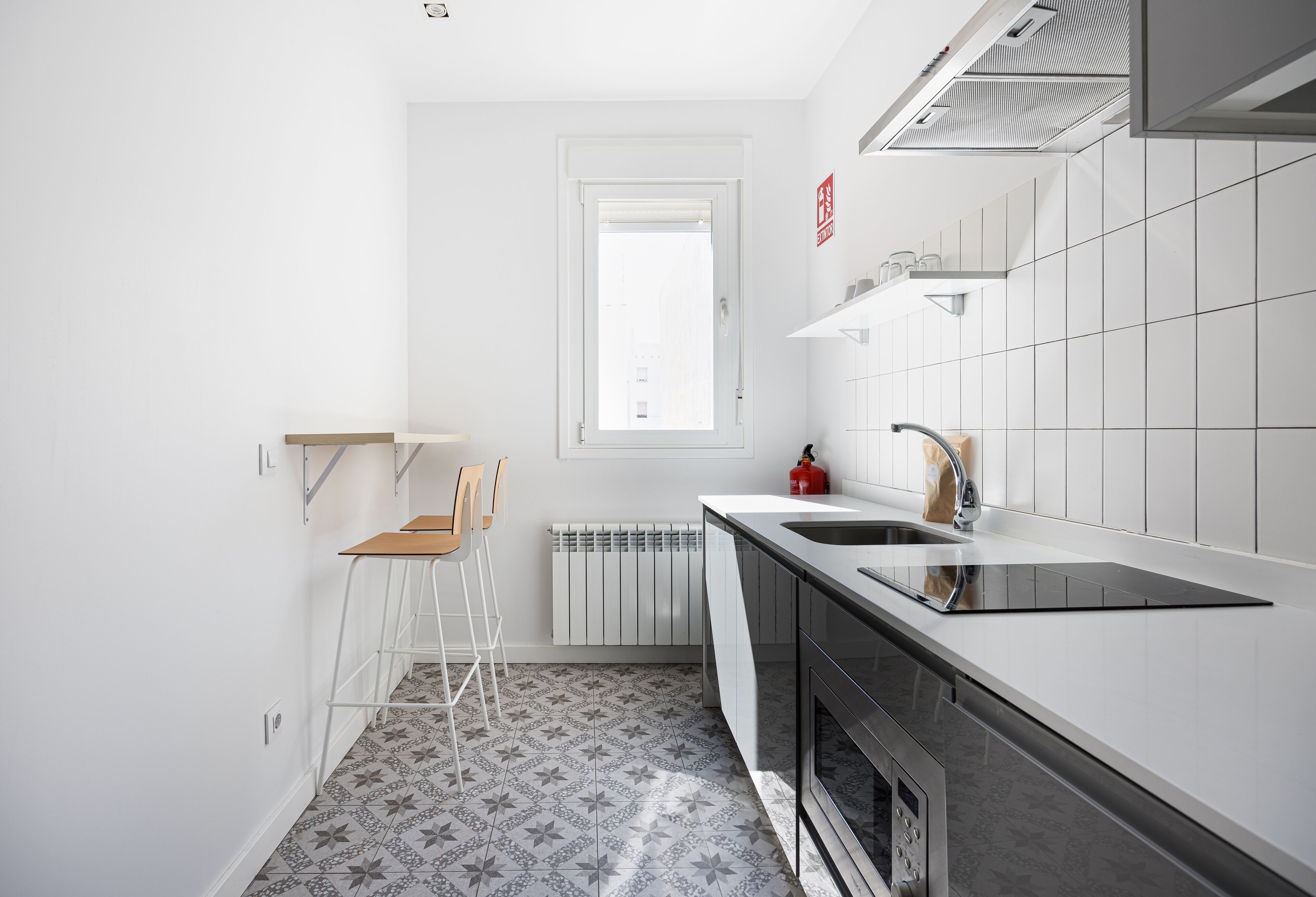 A modern kitchen with white cabinets, a black countertop, and a built-in oven.