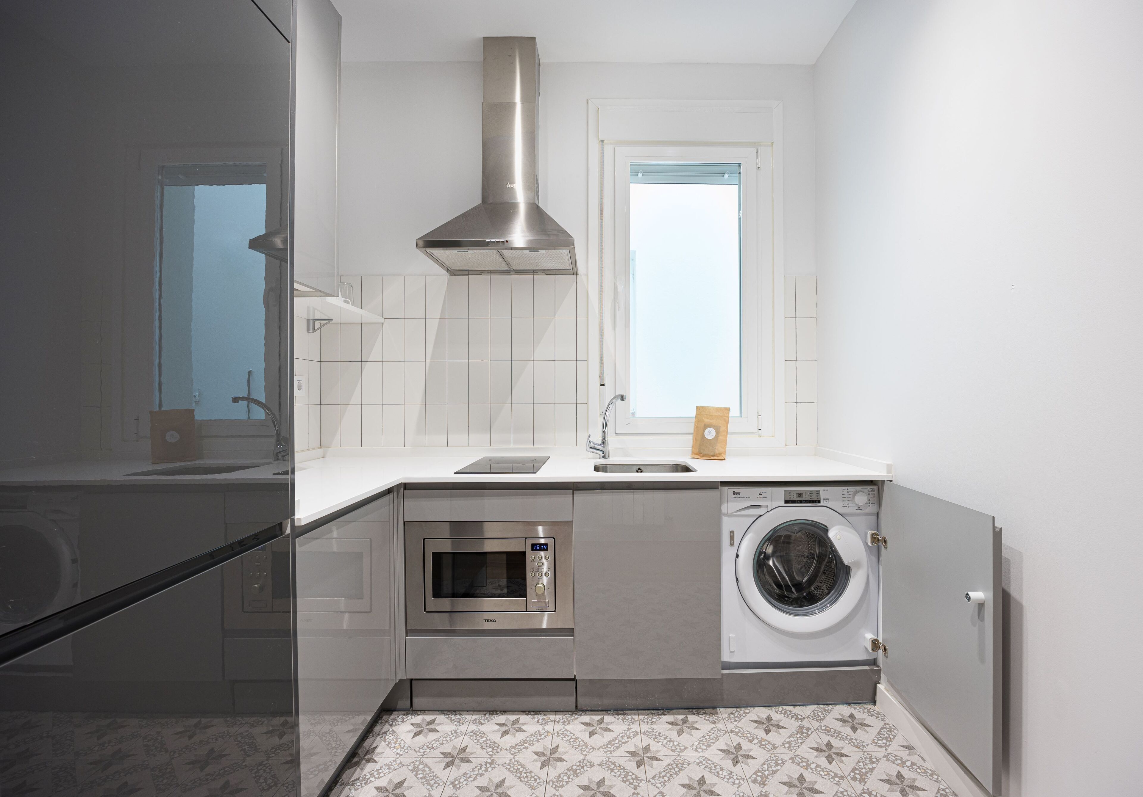 Une cuisine moderne équipée d’un four encastré, d’un four à micro-ondes et d’un lave-linge.