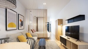Una sala de estar moderna con un sofá, una mesa de comedor, un televisor y un separador de madera.