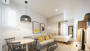Una sala moderna con comedor, un sofá, una mesa de centro y un televisor sobre un mueble.
