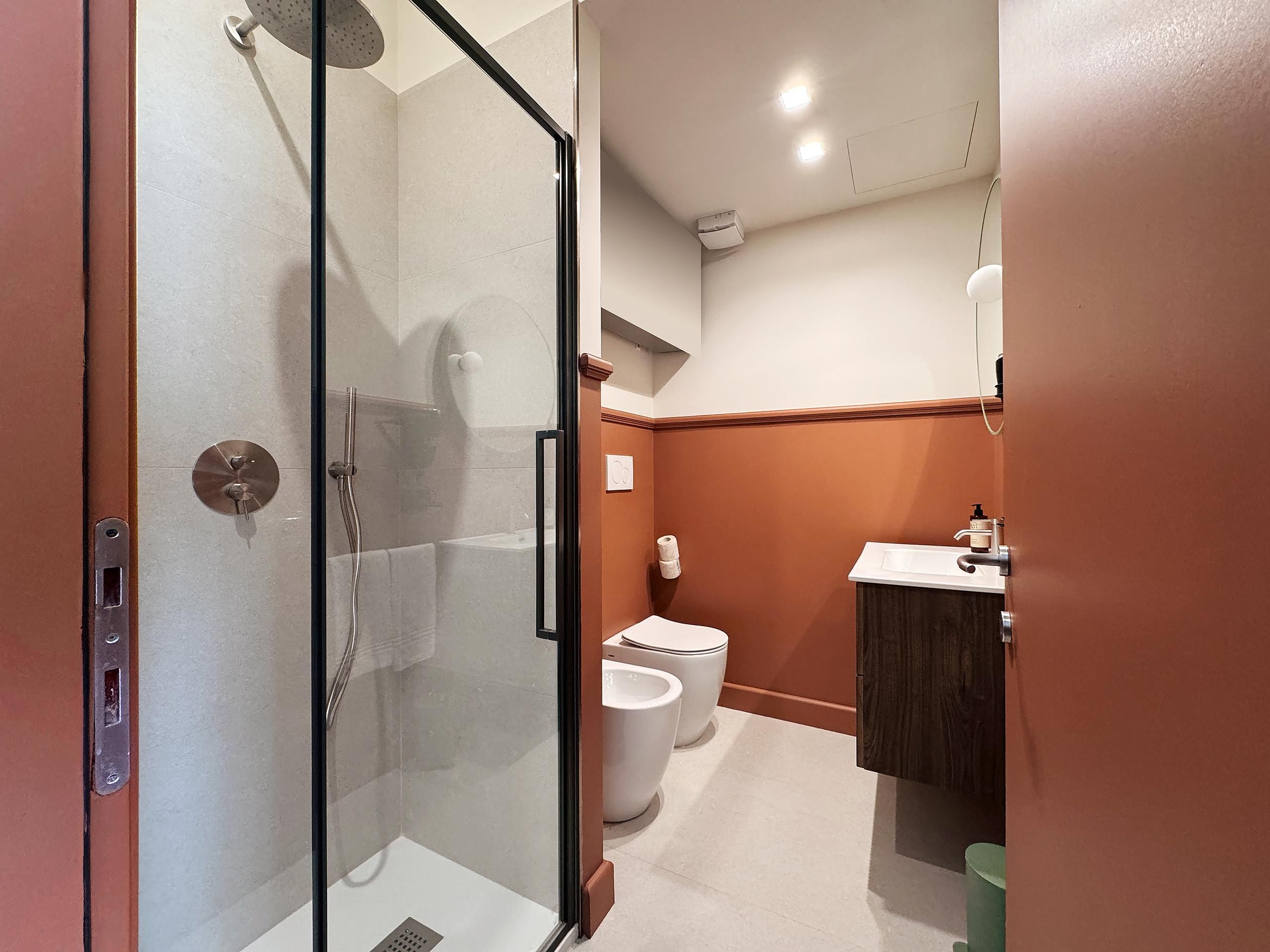 Un baño moderno con ducha envuelta en vidrio, inodoro y lavamanos.