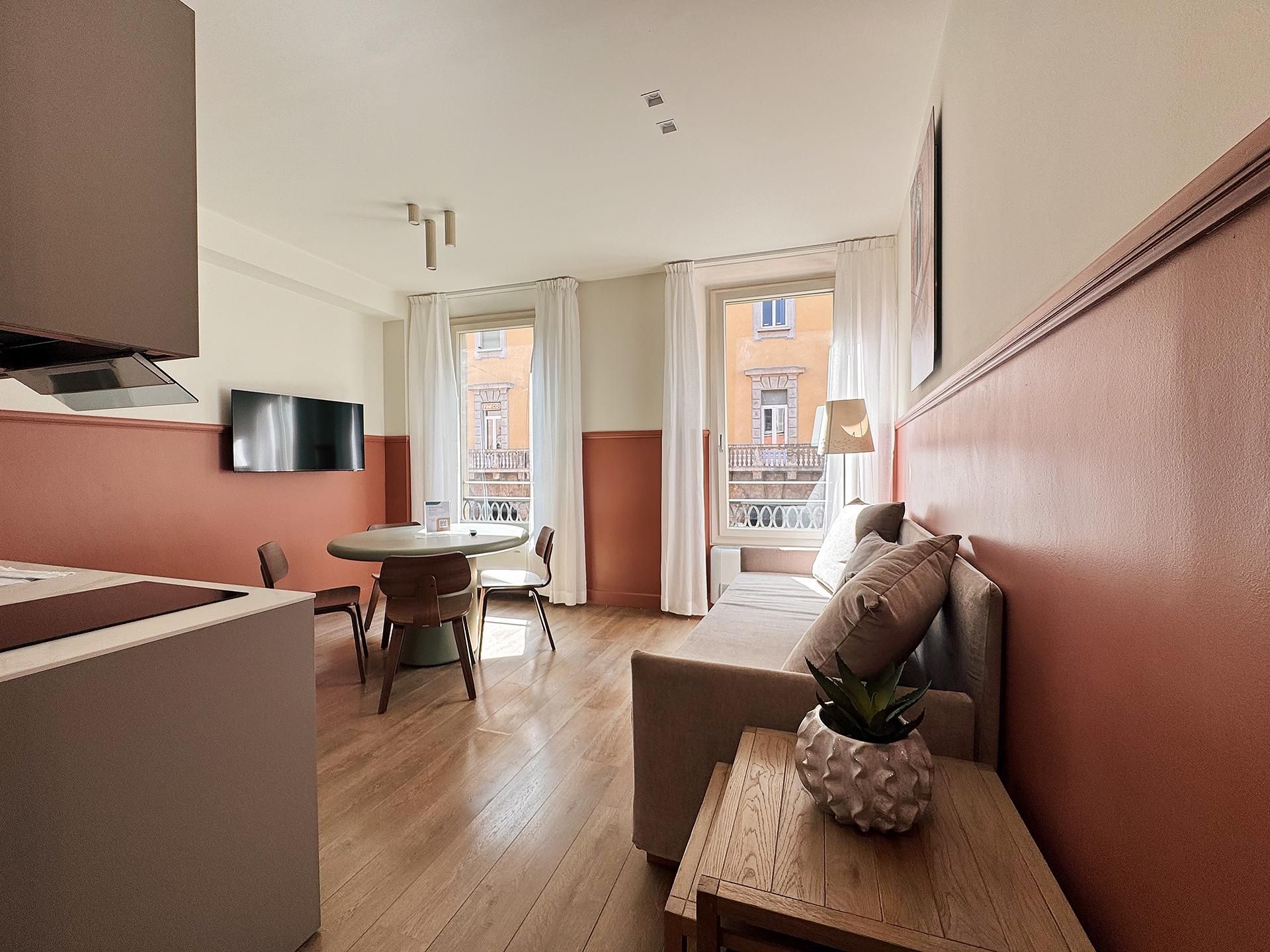 A compact living space with a dining area, a sofa, and a small table with a plant.