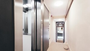 A narrow hallway with a carpeted floor, a door on the left, and a lit ceiling. - Mercanzia apartment. (Bologna)