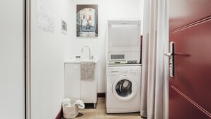 A compact laundry room with a washing machine, a dryer, and a small sink. - Mercanzia apartment. (Bologna)