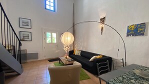 Ein Wohnzimmer mit einer Couch, einem Couchtisch, einer Lampe, einem Esstisch und einer Treppe.