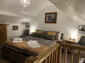A bedroom with a bed, a wooden headboard, a nightstand, a lamp, a framed picture on the wall, and a window with curtains.