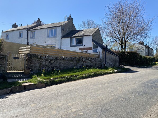 A two-story house with a stone wall and a wooden gate.
