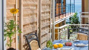 Eine Terrasse mit Esstisch, einem Korbsessel und Meerblick.
