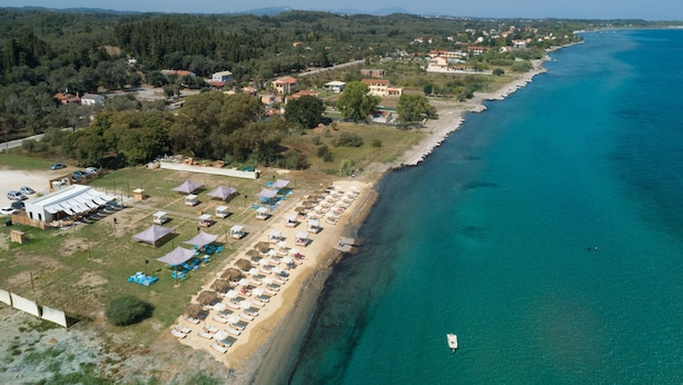 Luftaufnahme einer Küstenregion mit Strand, Zelten und einem kleinen Boot.
