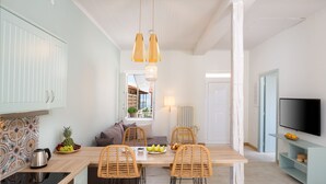 Eine moderne Küche mit Essbereich, ausgestattet mit einem Holztisch, Korbstühlen und einem Fernseher auf einem Schrank.