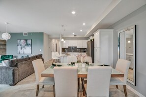 A modern kitchen with white cabinets, a central island, and a dining area with a table set for four.