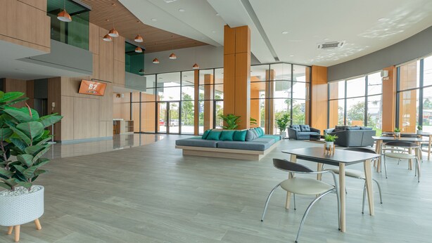 Un hall d’entrée spacieux au design moderne, comprenant un grand espace salon, un comptoir d’accueil et de grandes fenêtres laissant entrer la lumière naturelle.