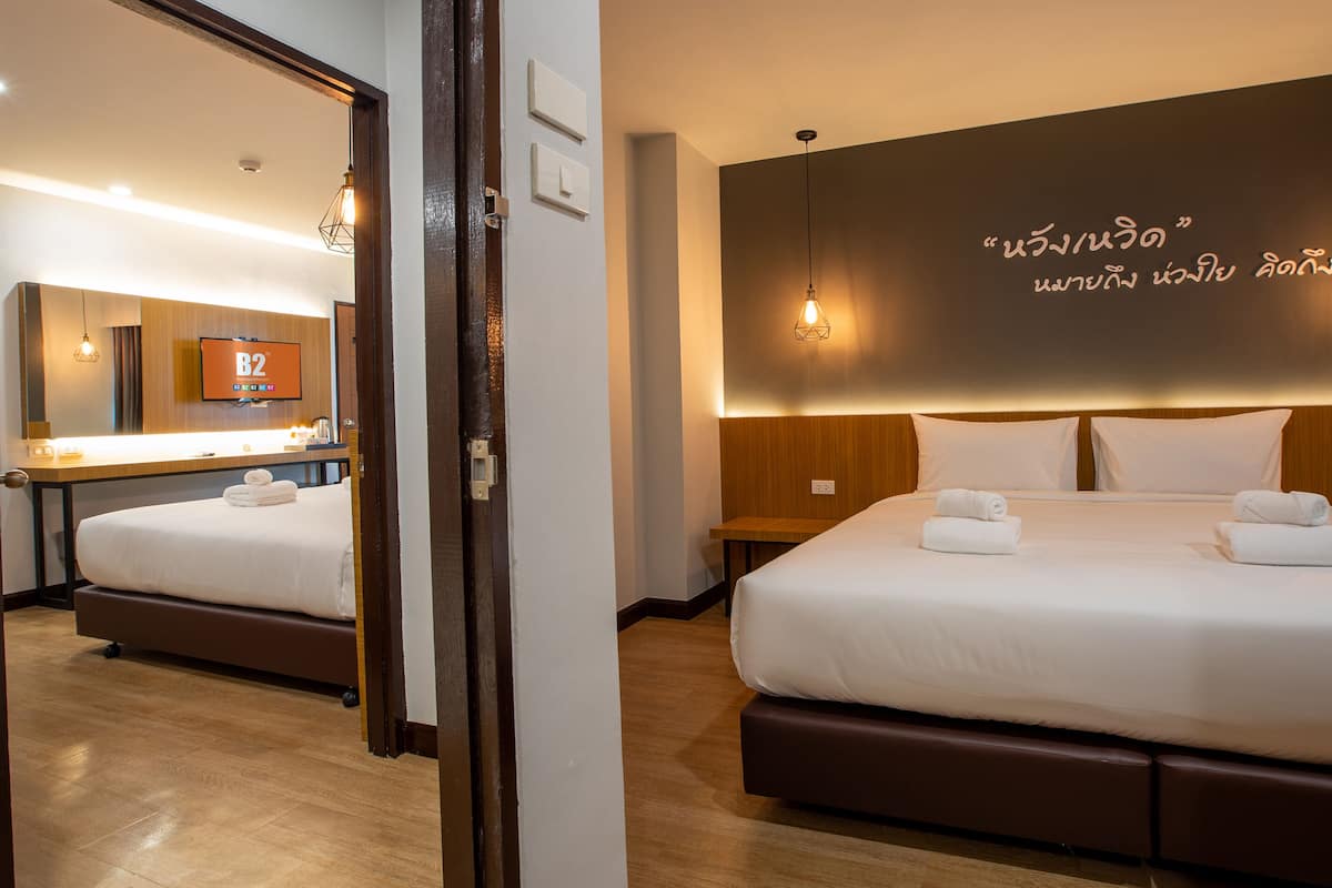 A hotel room with a large bed, a bedside table, a mirror, and a wall with a light fixture.