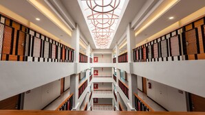 Un intérieur à plusieurs niveaux, doté d’un escalier central, de murs blancs et de panneaux en bois à motifs.