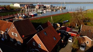 A marina with boats docked, a building with a red roof, and a grassy area in the foreground.