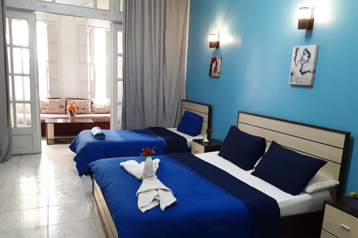A hotel room with three beds, a sofa, and a dining table.