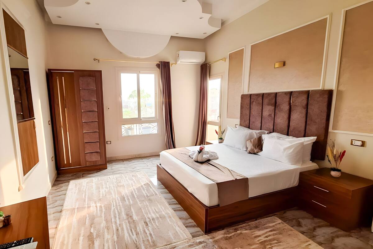 A bedroom with a large bed, wooden headboard, and a nightstand with a lamp.