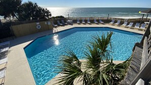 A clear blue pool with a wooden deck, lounge chairs, and a view of the ocean. - Gated resort on CSB.End unit w/easy walk to beach. Beach cart & chairs included. (Port St Joe)