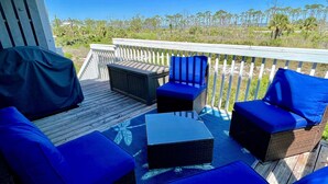 A deck with outdoor furniture, including sofas and chairs, overlooking a natural landscape with trees and a body of water. - Gated resort on CSB.End unit w/easy walk to beach. Beach cart & chairs included. (Port St Joe)