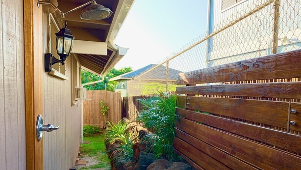 A narrow pathway leading to a wooden door with a metal handle, flanked by a wooden fence and a chain-link fence. - Diamond Head/Waikiki Surf Shack 2-Bedroom Private Ohana Unit (Honolulu)