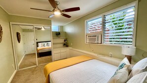 A bedroom with a bed, a ceiling fan, a window with blinds, a bedside lamp, and a small desk area. - Diamond Head/Waikiki Surf Shack 2-Bedroom Private Ohana Unit (Honolulu)