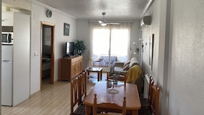 Un espacio habitable compacto con comedor, kitchenette y balcón.