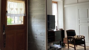 Una stanza con una porta in legno, un televisore su un mobile, una poltrona con motivo leopardato e un pavimento in legno.