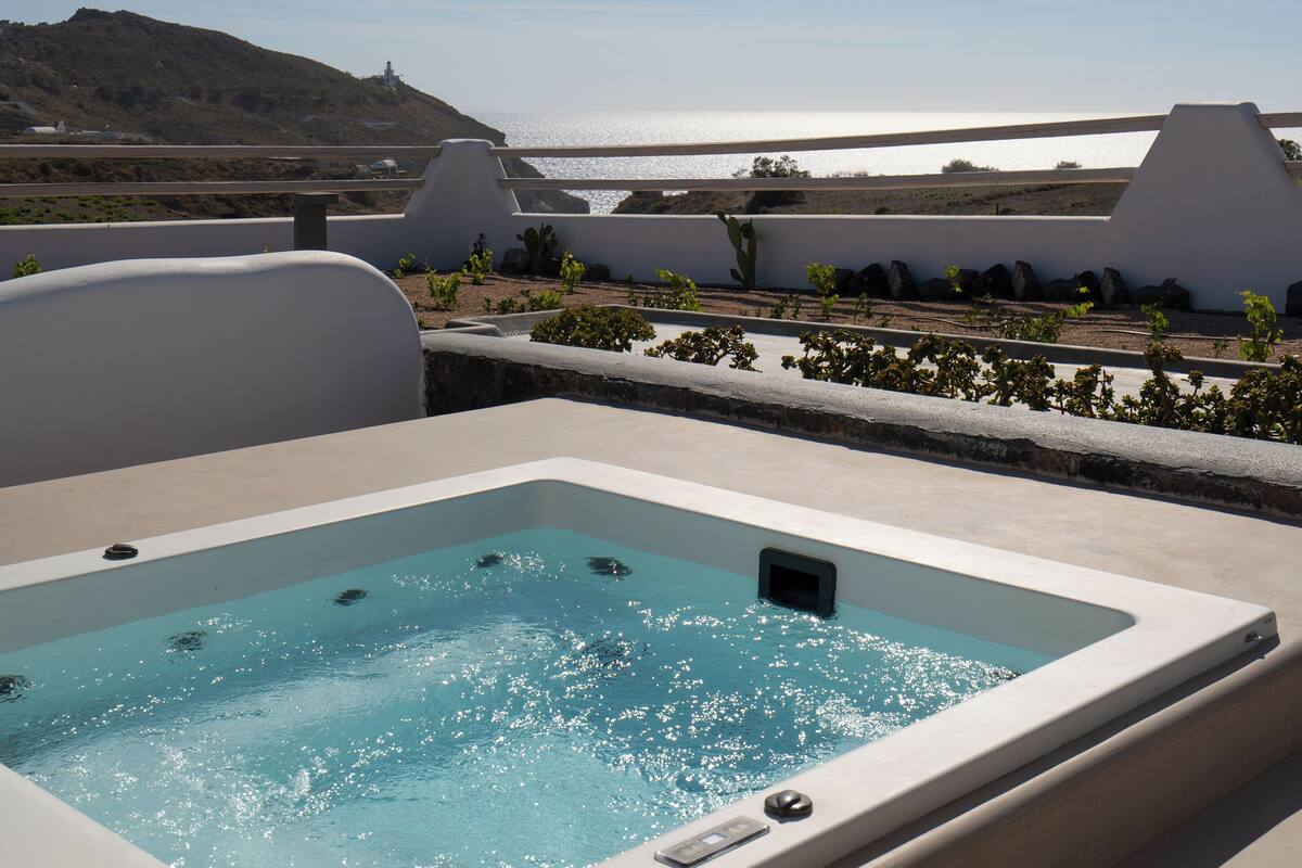 A rooftop pool with a clear view of the sea and a hilly landscape in the background.