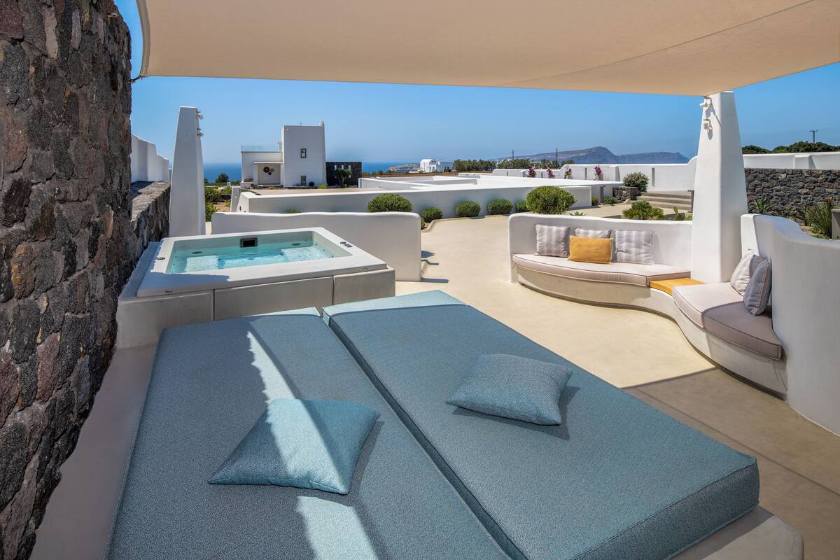 A rooftop terrace with a hot tub, lounge chairs, and a view of the sea.