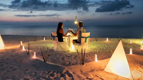 A couple dining at a table with a view of the ocean at dusk. - La Ponta Villas & Suites (Santorini)