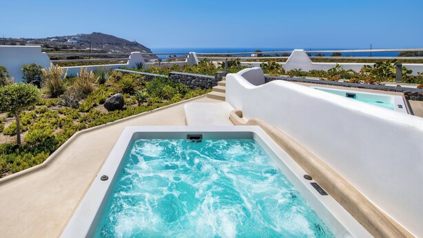 Un jacuzzi con vistas al océano y un paisaje montañoso.