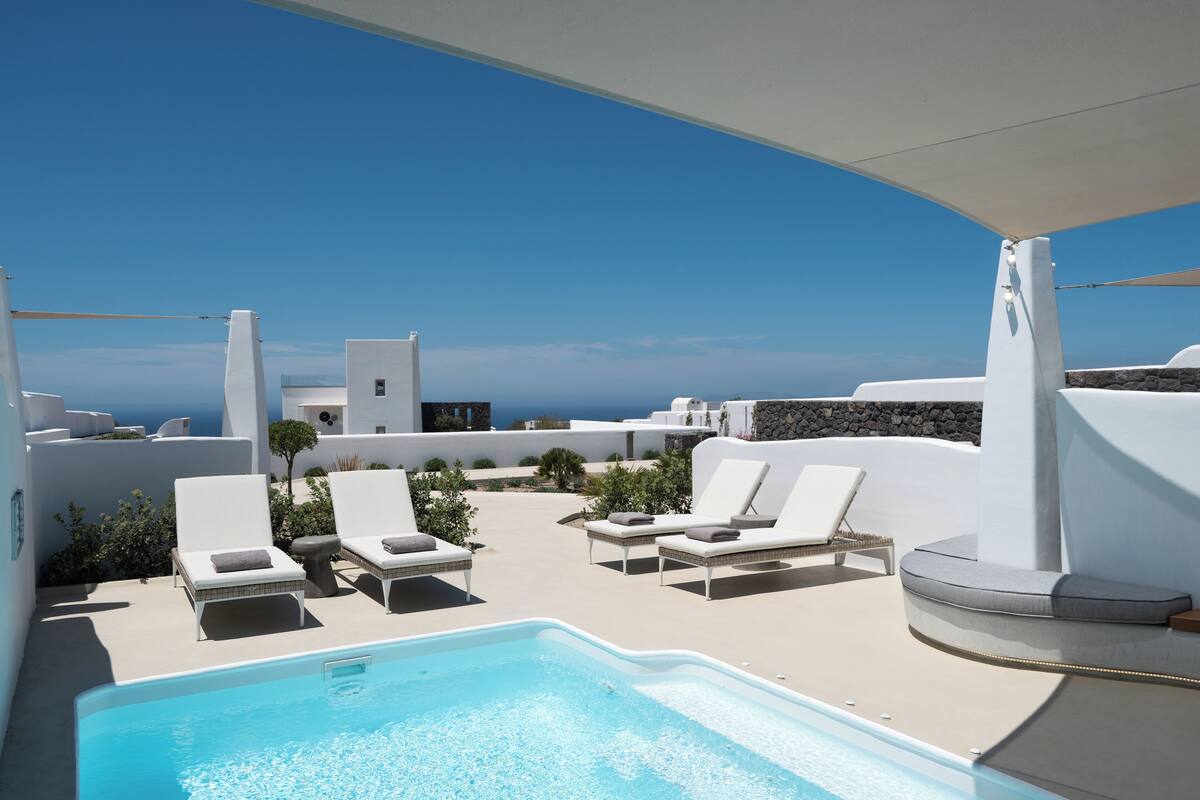 A poolside area with lounge chairs and a view of the sea.