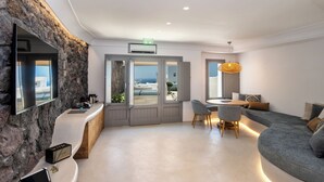 Un moderno vestíbulo de hotel con una pared de piedra, un mostrador de recepción, una zona de estar con un sofá y sillones, y un ventanal con vistas al mar.