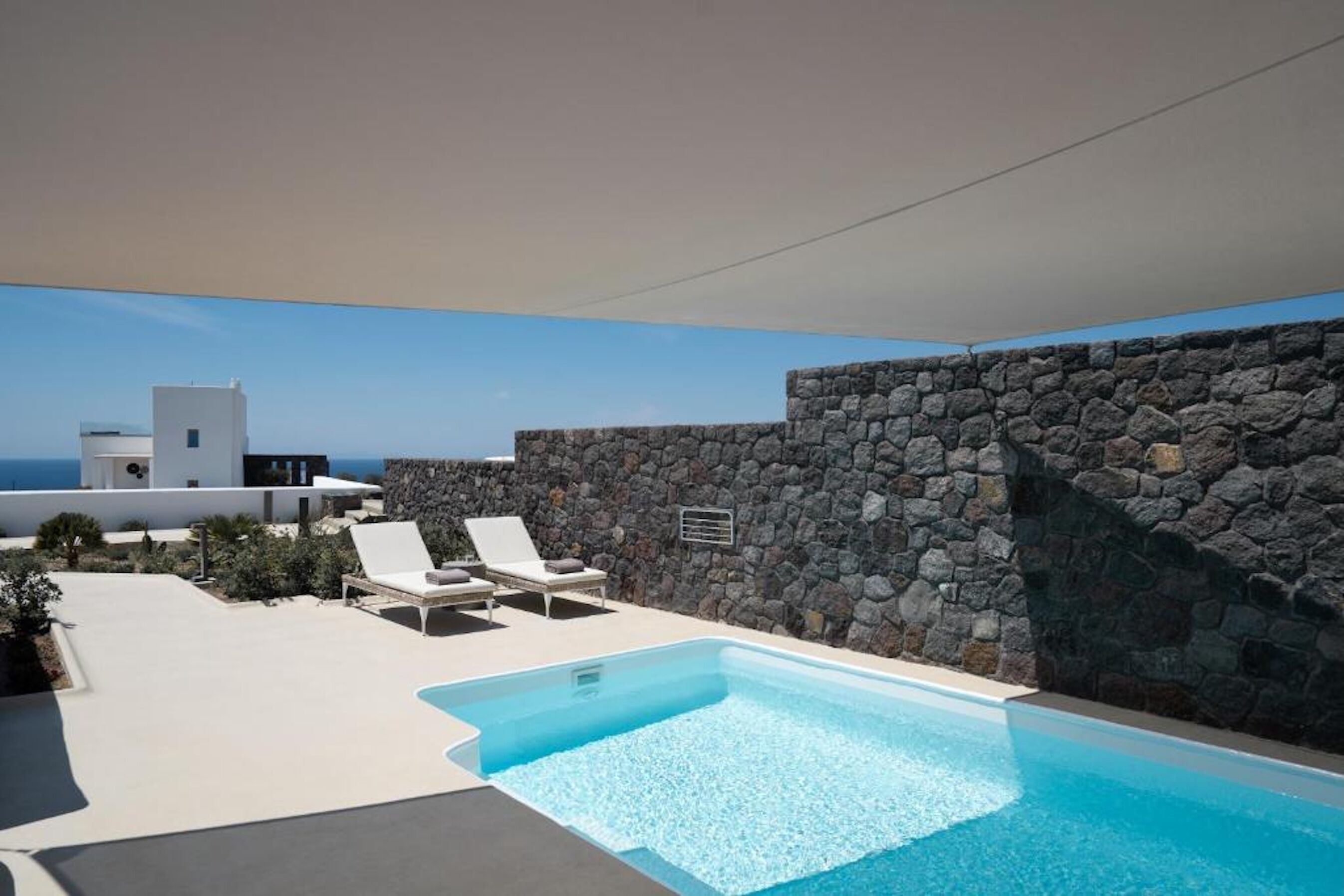 Una piscina al aire libre, sillones reclinables de piscina