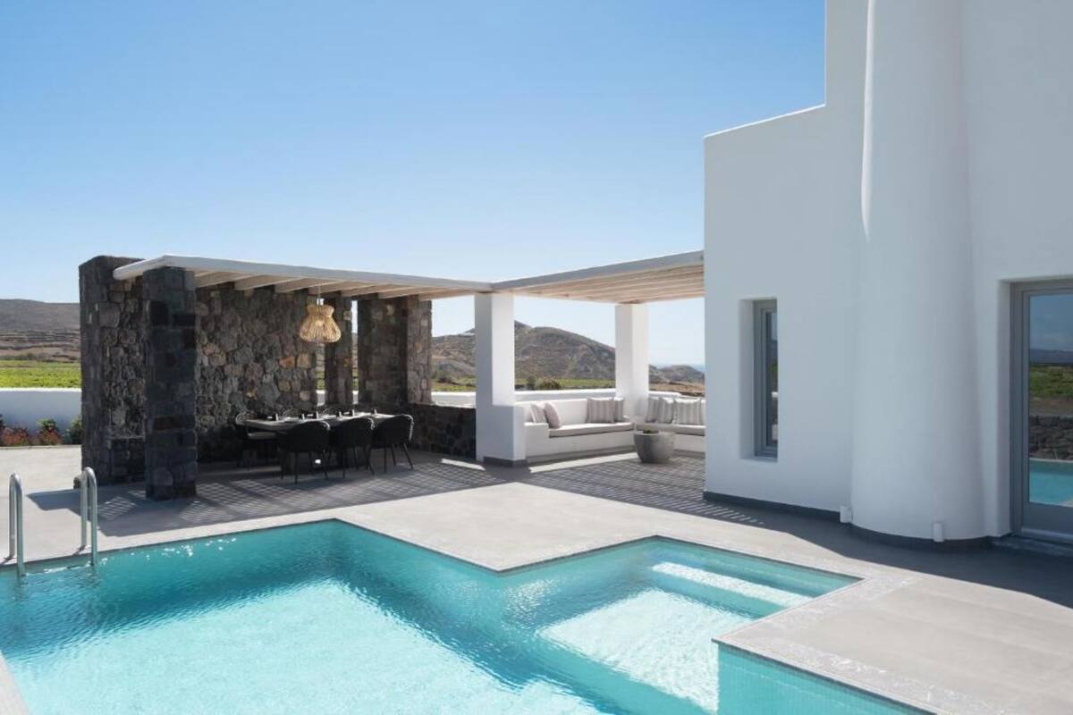 A modern outdoor pool area with a stone structure, seating, and a view of the landscape.