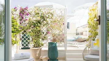 A sunlit patio with a white lattice, a teal vase, and a lounge chair.