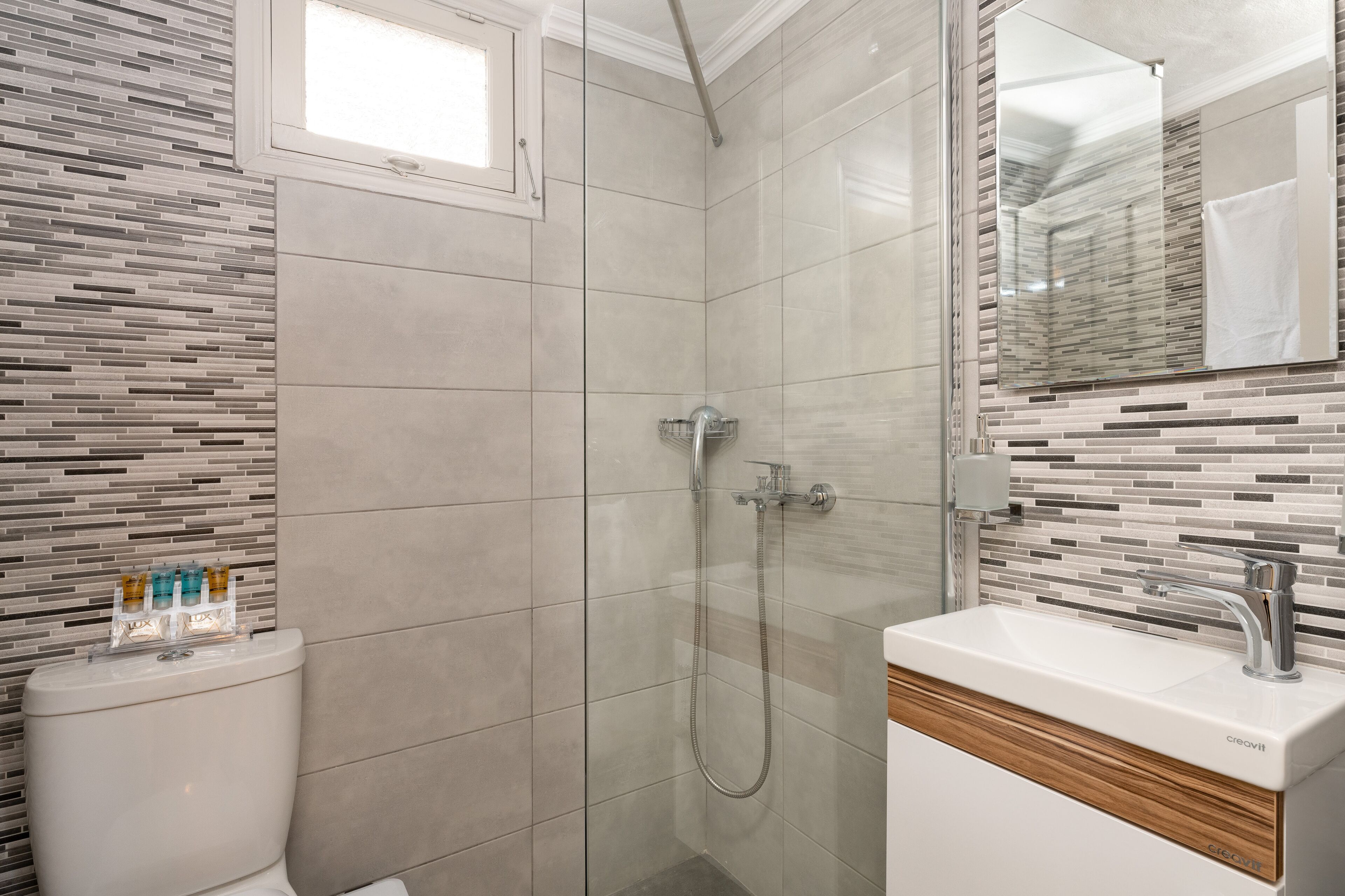A modern bathroom with a shower, toilet, and sink.
