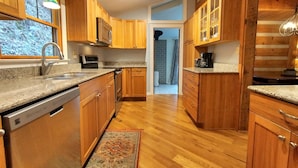 Una cucina moderna con mobili in legno, piani in granito, elettrodomestici in acciaio inossidabile e vista verso l'esterno.