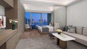A modern hotel room with a bed, a sofa, a desk, and a view of the cityscape. - Star Residence ICC Guangzhou (Guangzhou)