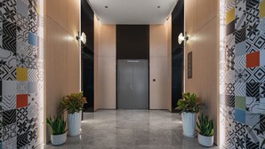 A modern hallway with patterned walls, two potted plants, and a door at the end. - Star Residence ICC Guangzhou (Guangzhou)